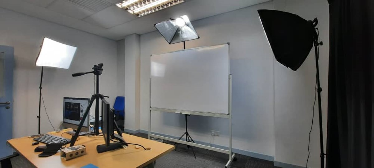Wide view featuring working desk, light fixtures and a whiteboard in Sunway University’s recording room