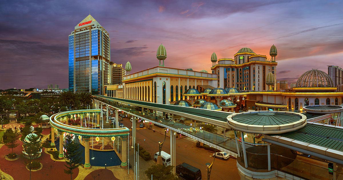 A wide-shot of Sunway Canopy Walk at dusk, featuring an illuminated The Pinnacle Sunway, Sunway Resort and Sunway Pyramid in the background