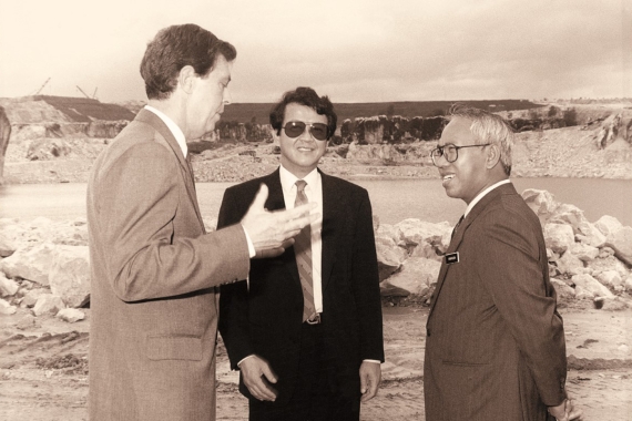 A black-and-white medium wide shot of young Tan Sri Dr. Jeffrey Cheah, flanked by Tan Sri Sabaruddin Chik and another on the tin-mining wasteland (now SCKL) in the 1980s.