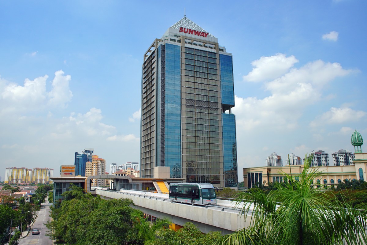 A wide-shot of BRT-Sunway in motion on its elevated dedicated track in daytime with The Pinnacle Sunway and Sunway Pyramid in the background