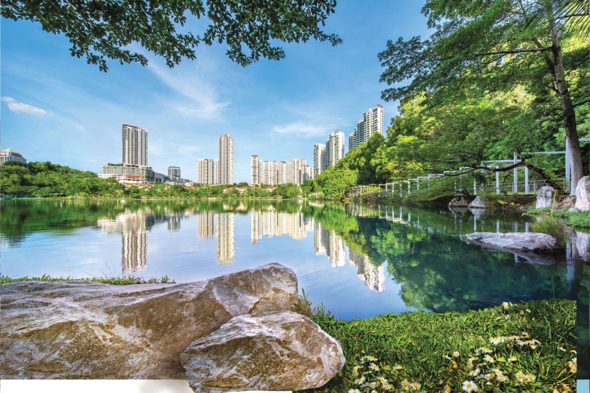 A wide shot of Sunway’s water treatment plant in South Quay, angled from under a shady tree right behind a boulder, featuring the beautiful city skyline, lush greeneries and bright, blue sky mirrored perfectly in the lake water.