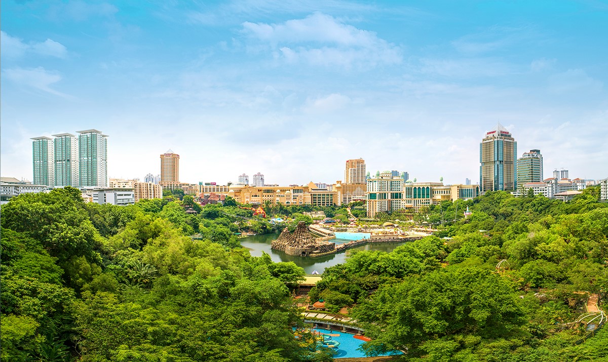 A wide shot of daytime Sunway City Kuala Lumpur featuring Sunway Lagoon and the city skyline nestled amidst lush greeneries