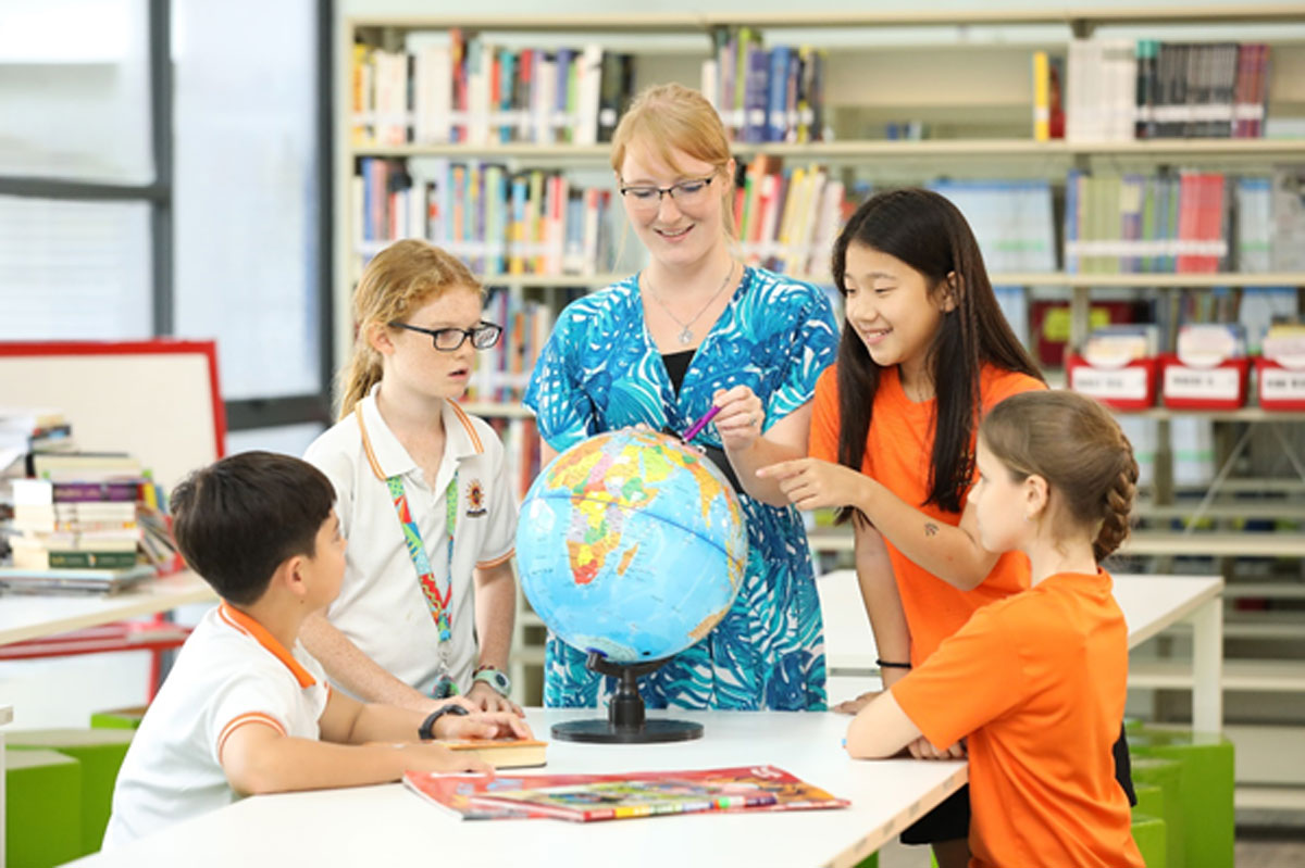 An SIS teacher exploring and learning with her students with a globe in a classroom