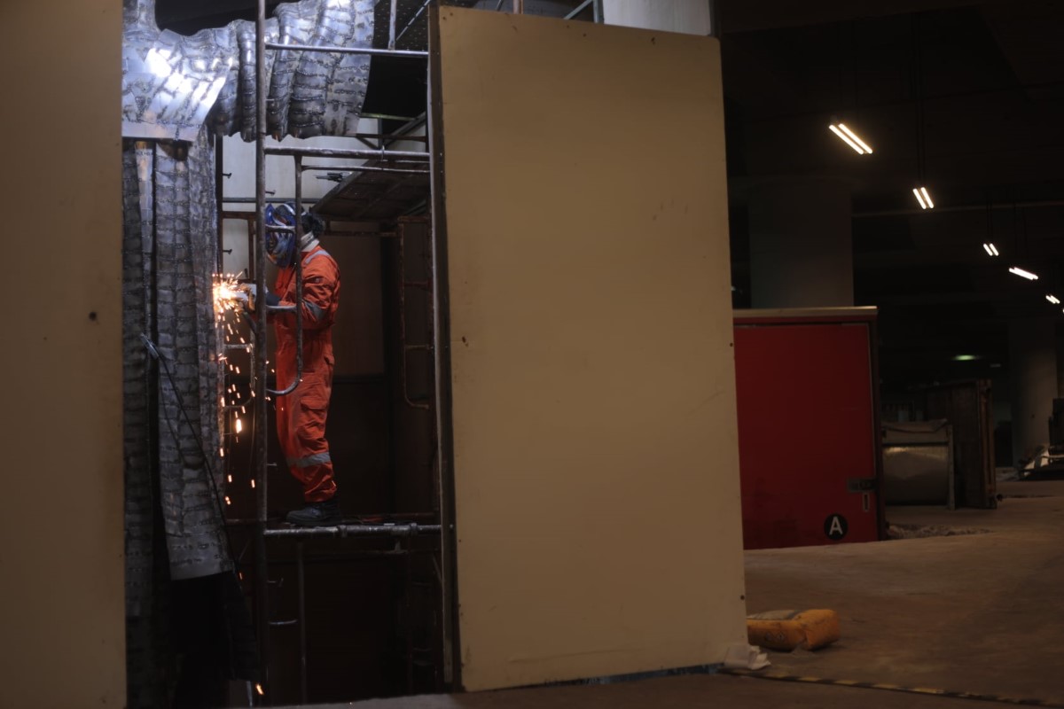 A wide shot of Infantino cutting steel during the process of putting together sculpture ‘Destiny’ on elevated brackets