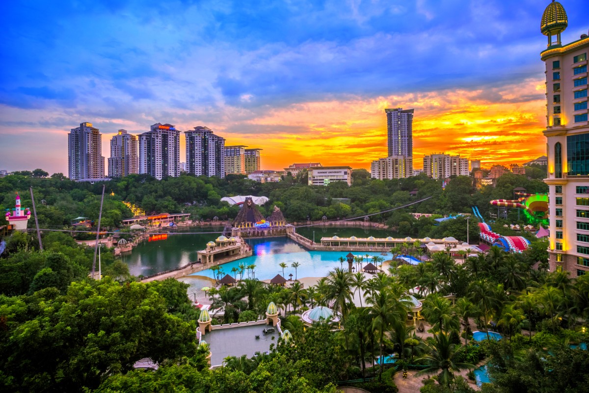 A wide-angle panorama shot of present-day Sunway Lagoon Theme Park, featuring the peak of sunset at the horizon.