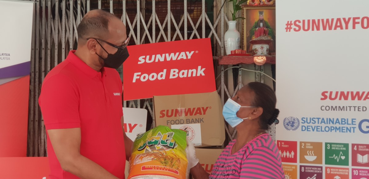 Bernard Paul giving a bag of rice and essential items to a happy beneficiary