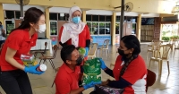 Sunway staff clad in red providing bags of rice and essential groceries to the beneficiaries