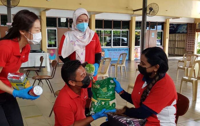 Sunway staff clad in red providing bags of rice and essential groceries to the beneficiaries