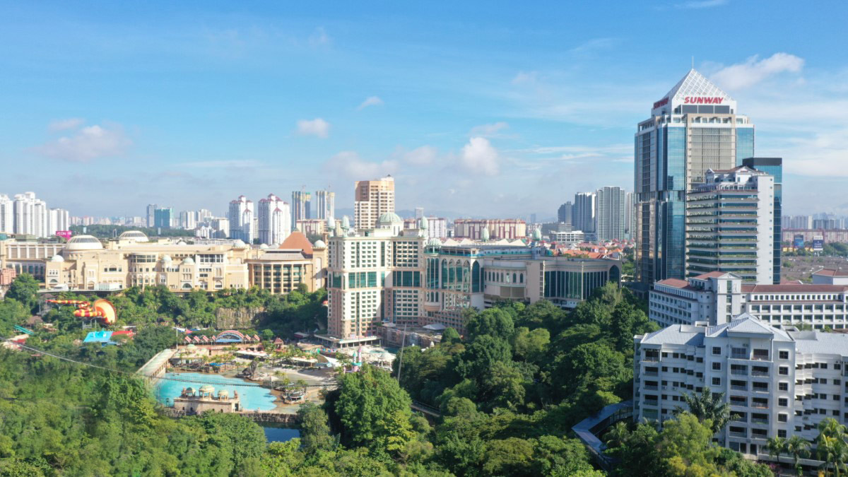 A wide shot of Sunway City Kuala Lumpur at daytime, featuring Menara Sunway, Sunway Pinnacle, Sunway Resort, Sunway Pyramid and Sunway Lagoon surrounded by lush greenscapes in the frame, outlined by Kuala Lumpur city line and clear, blue sky.