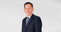 A mid-shot of Sunway Malls & Theme Parks chief executive officer HC Chan, dressed smartly in proper suit and polka dot blue tie, standing at an angle in front of a clear white backdrop