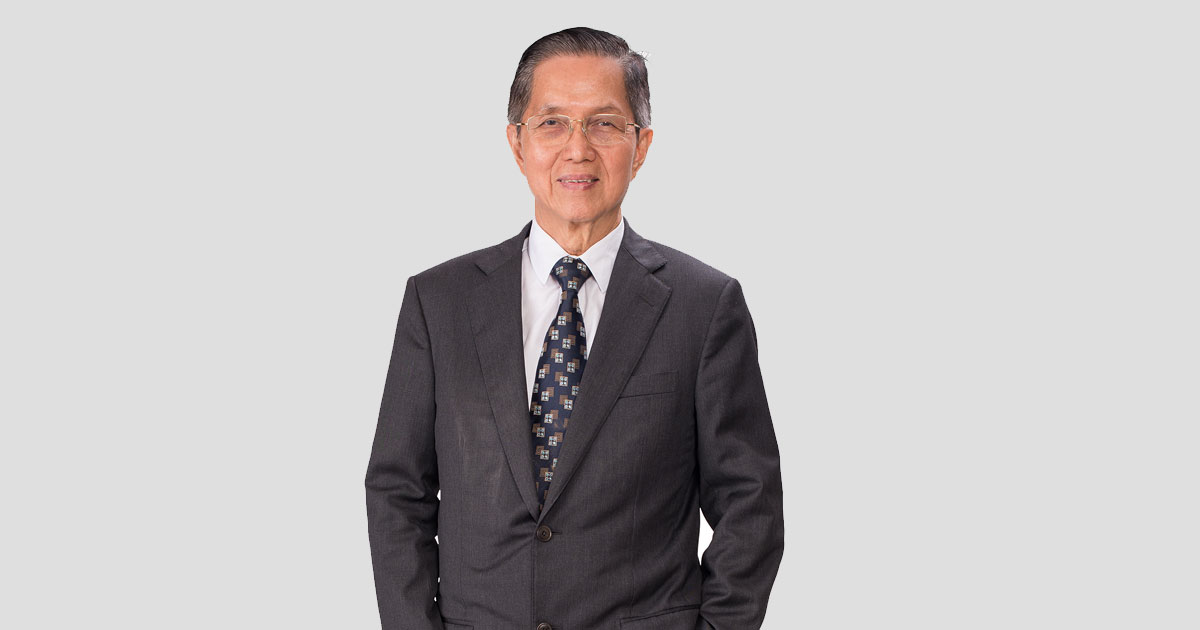 A portrait medium shot of Sunway Group President Tan Sri Chew Chee Kin, dressed immaculately in black suit, white button up and printed navy tie, with one hand kept in his trouser pocket while another hand is kept out