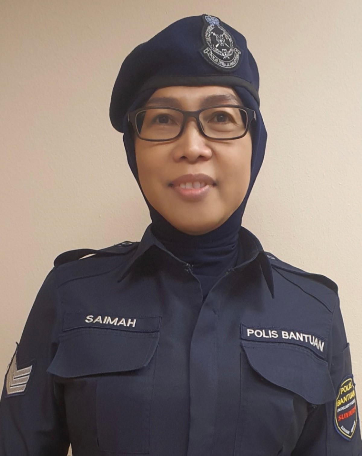 A half body shot of Saimah Abdul Jalil smiling in her complete uniform as a policewoman.