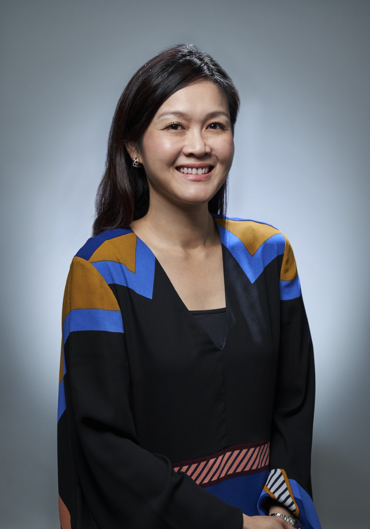 A half body shot of Sarena Cheah in a yellow top and black blazer infront of a white background.