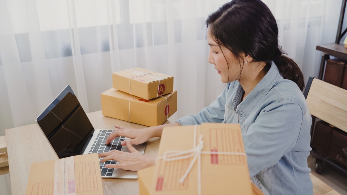Woman doing online shopping. With a multitude of boxes and packages that she ordered on her table.