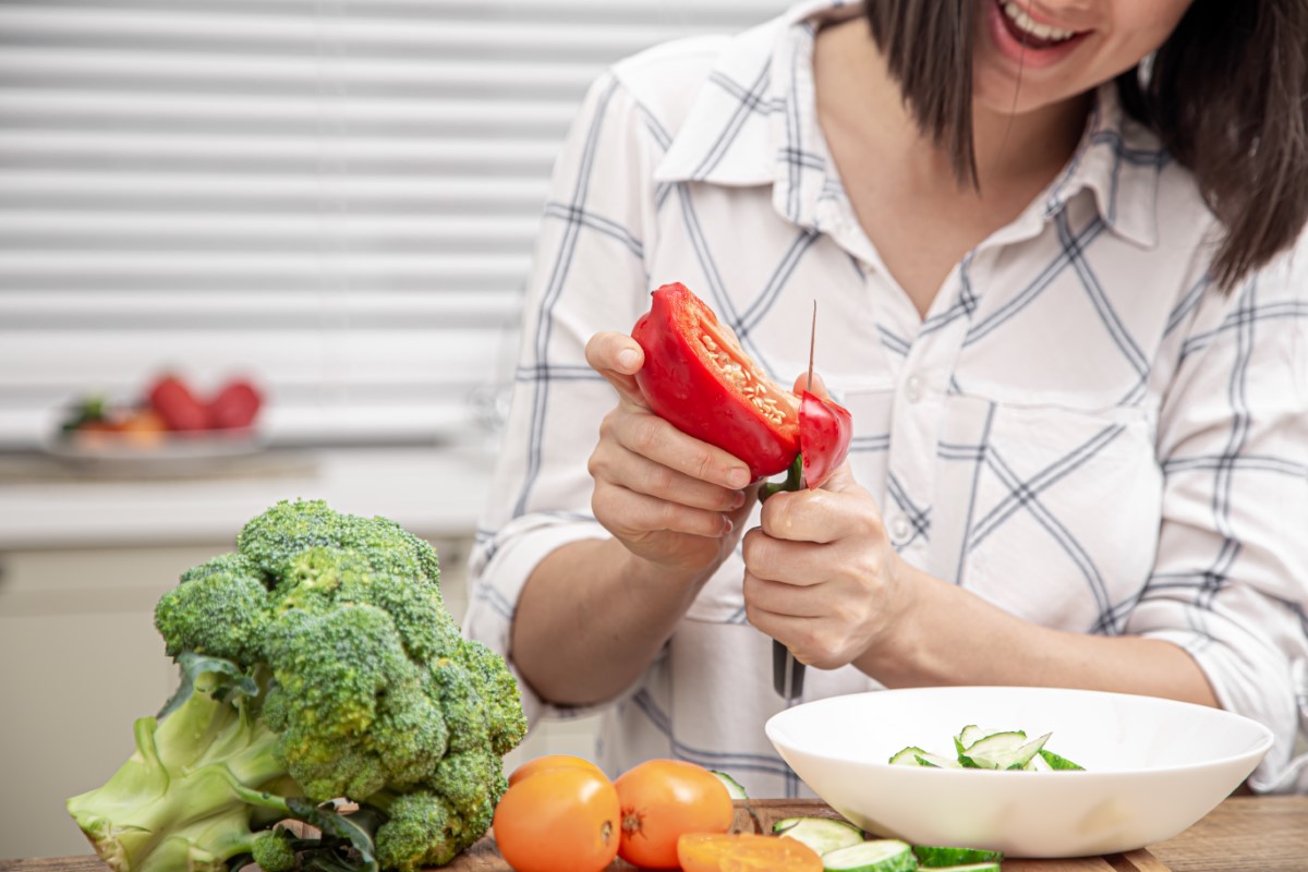 Woman cutting vegetables and placing them in a bowl.