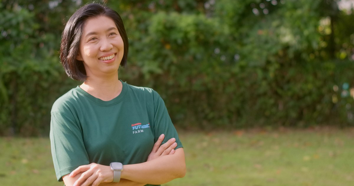 A landscape mid shot of Sunway XFarms’ Yvonne in signature green Sunway FutureX tee, looking ahead smiling brightly with both arms folded
