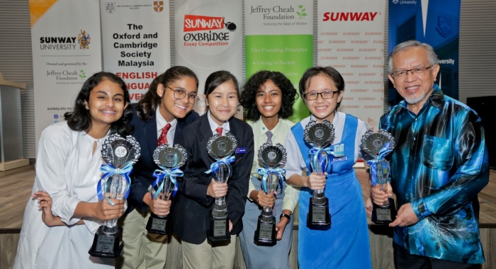 A medium full landscape shot of Sunway-Oxbridge Essay Competition’s Top Six (including representatives) holding up their respective trophies during the award-giving ceremony in July 2019