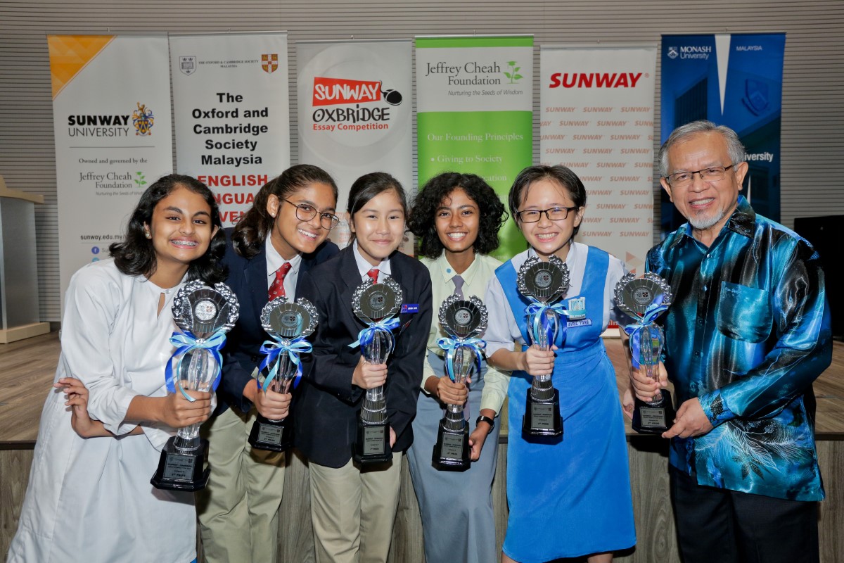 A medium full landscape shot of Sunway-Oxbridge Essay Competition’s Top Six (including representatives) holding up their respective trophies during the award-giving ceremony in July 2019