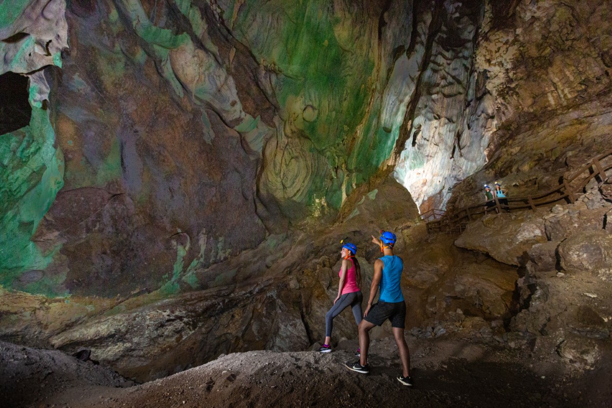 A side-angle shot of two hikers appreciating the artworks on the walls of Picasso Cave at Sunway City Ipoh