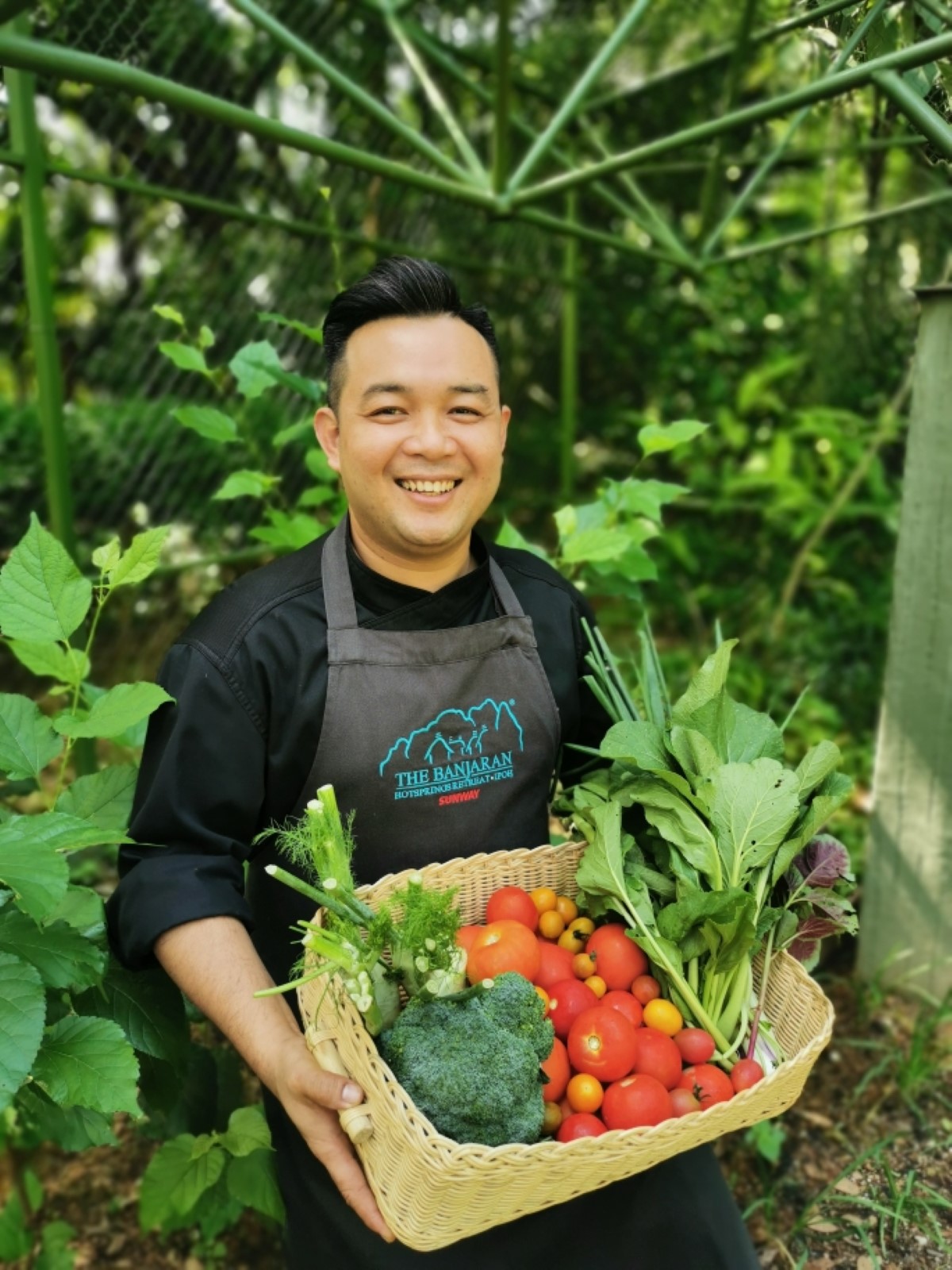 A portrait-shot of Chef Lee Choon Boon carrying a basket of vegetables