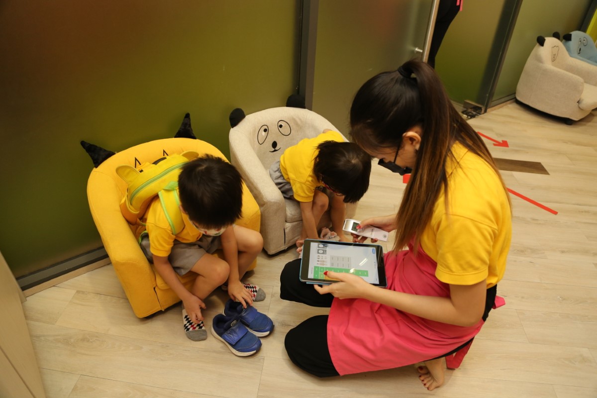 A landscape shot of a Sunway Little Sunshine homeroom teacher helping toddlers check-in the Oodlins app upon arrival