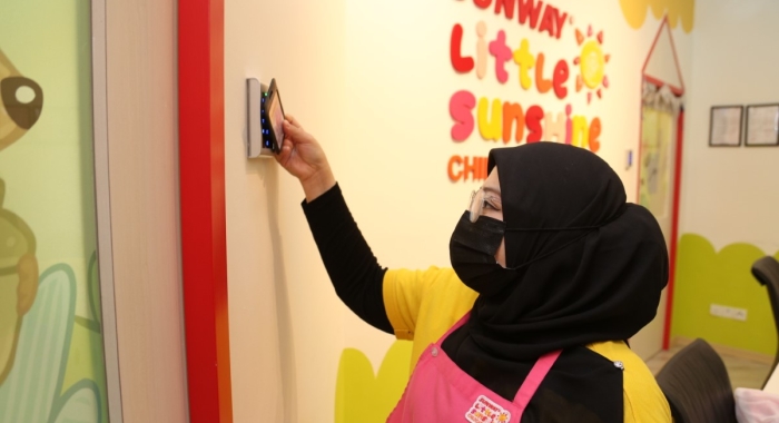 A loose close up shot of a Sunway Little Sunshine homeroom teacher tapping her access card to enter the main area