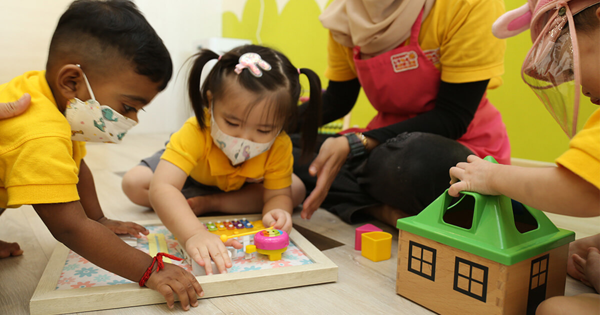 A medium landscape shot of a Sunway Little Sunshine Childcare Centre guiding young toddlers using sensory learning materials