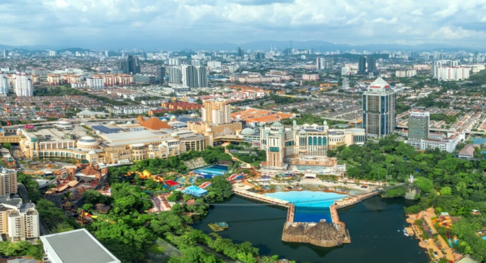 An aerial view of Sunway City Kuala Lumpur, with Sunway Lagoon and the Sunway Lagoon lake in view alongside Sunway Resort and Sunway Pyramid, amidst sprawling greenery and trees