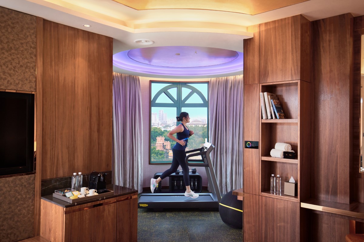 A female working out on the treadmill in the background, with wooden interior and bookshelves in the foreground.