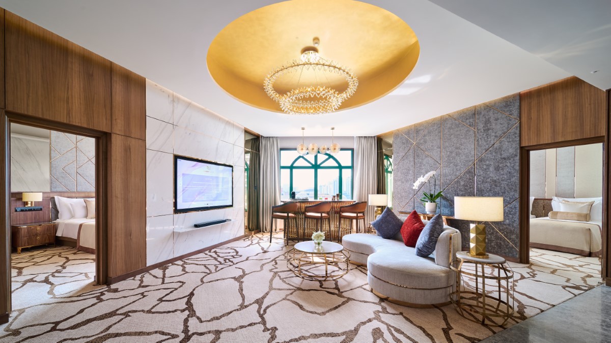 The Grand suite that features a grandiose living area - decorated with a chandelier, comfortable sofa and coffee table, with the bedrooms in the background.