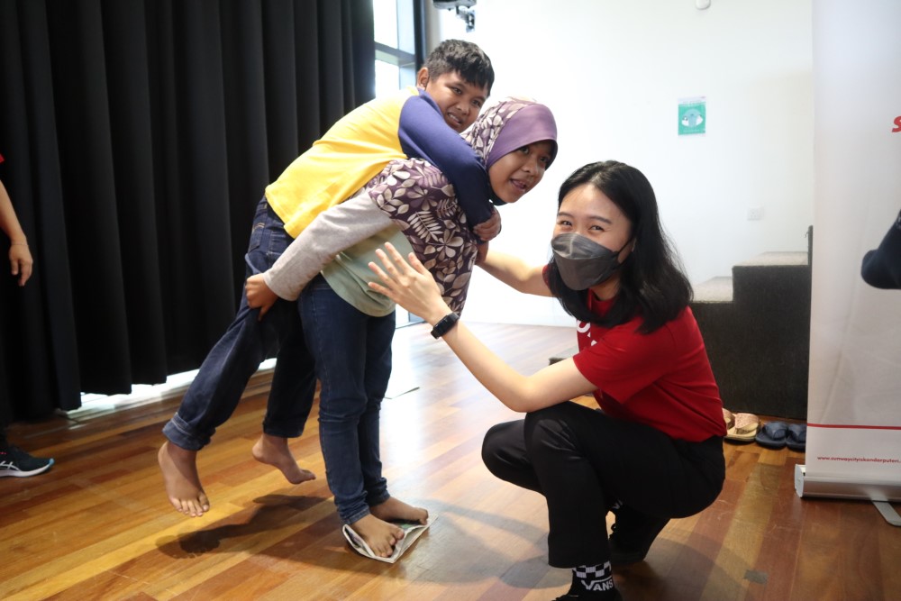 A cheerful Sunway staff playing alongside two children.