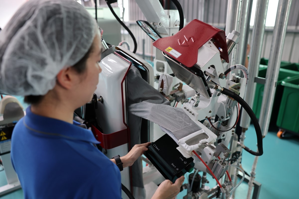 Candid shot of worker operating a Sankosha machine