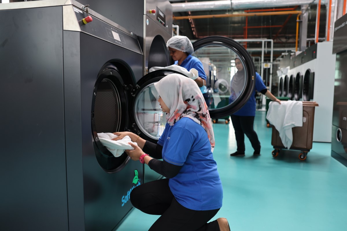 Candid shot of workers at the laundry plant operating the machines