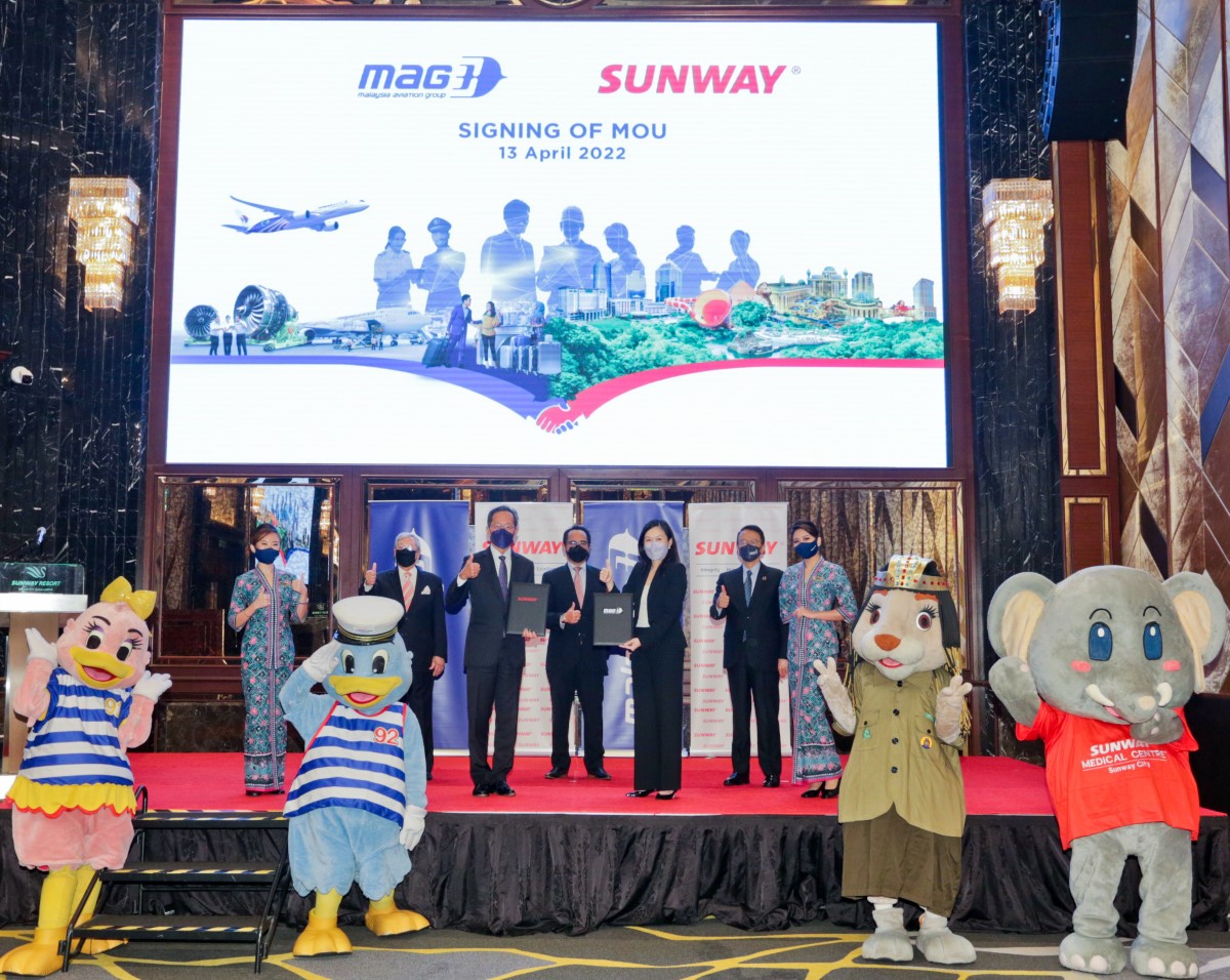 A full landscape shot of prominent Sunway Group and Sunway Aviation Group representatives on-stage alongside Malaysian Airlines stewardesses and Sunway City Kuala Lumpur mascots commemorating the finale of the MoU signing session.