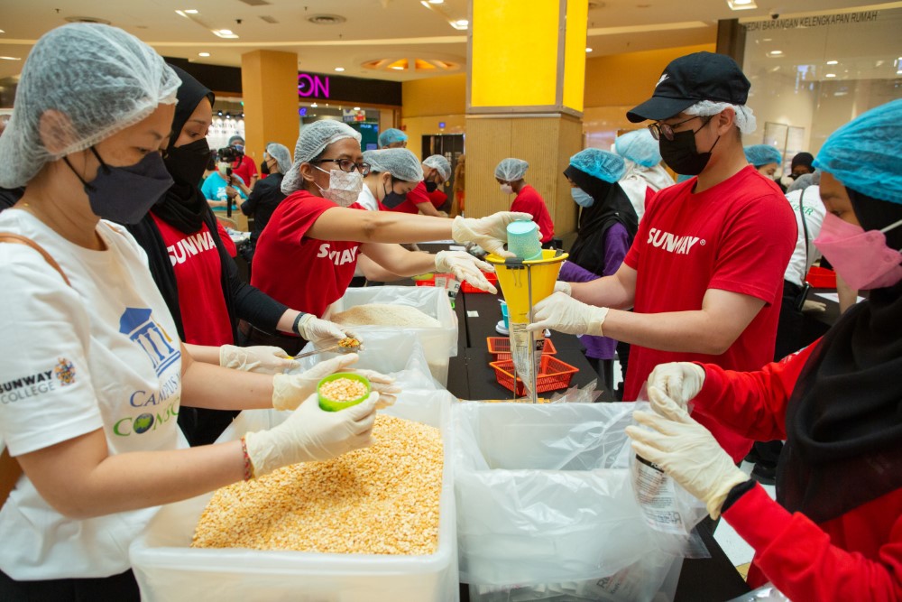 A medium landscape shot of Sunway volunteers in action during Sunway Meal Pack-a-Thon 2022 at Sunway Pyramid, Sunway City Kuala Lumpur.