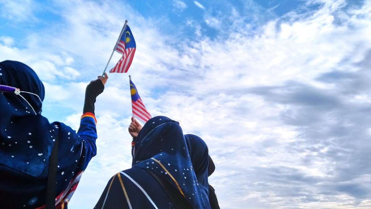 A shot of three individuals waving the Malaysia flag