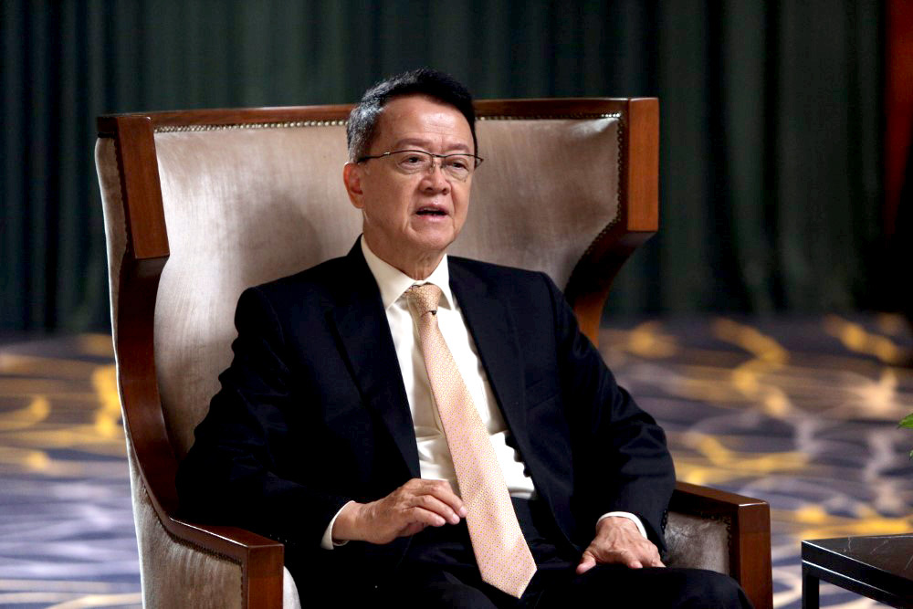 A medium landscape shot of Sunway Group founder and chairman Tan Sri Dr. Jeffrey Cheah AO, seated on a tall armchair amidst a dark setting