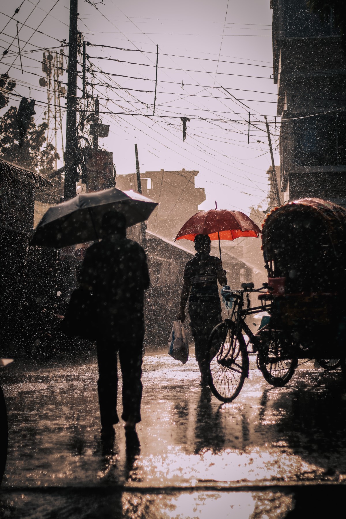 A full portrait shot of monsoon season, featuring people holding umbrellas on the street under a sepia light