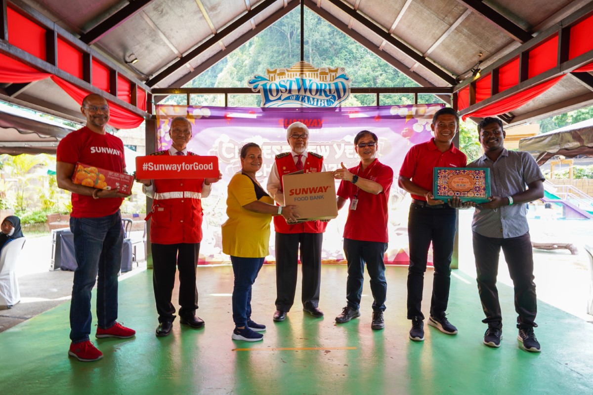 Sunway Group representatives handing over food boxes as well as Mandarin oranges to B40 beneficiaries, set amidst The Lost World Of Tambun background.