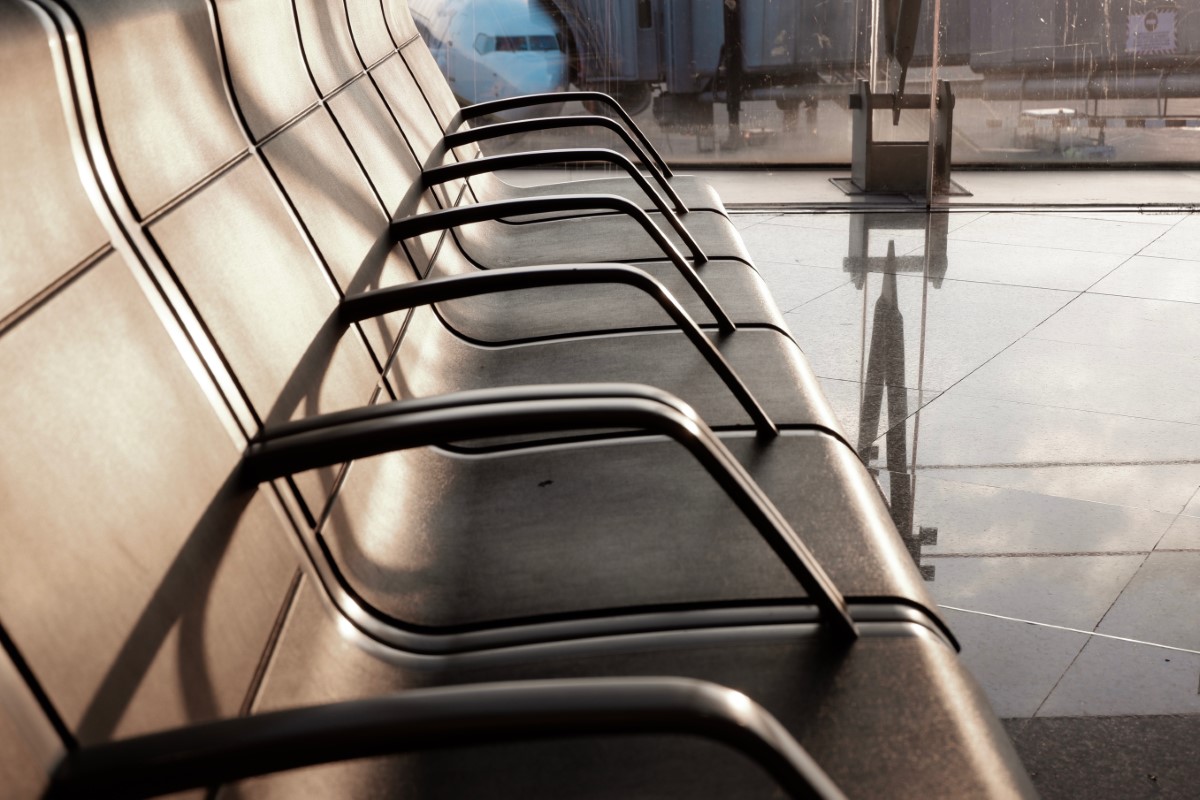 Empty airport chairs and a glossy floor, with the morning sun beaming down on the chairs.