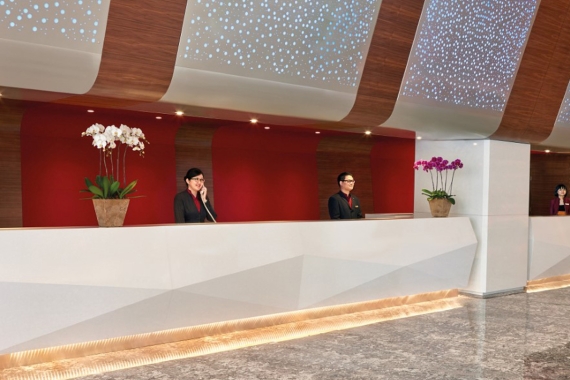 The front office of Sunway Pyramid Hotel where guests may check in, adorned with red walls and lit walls.