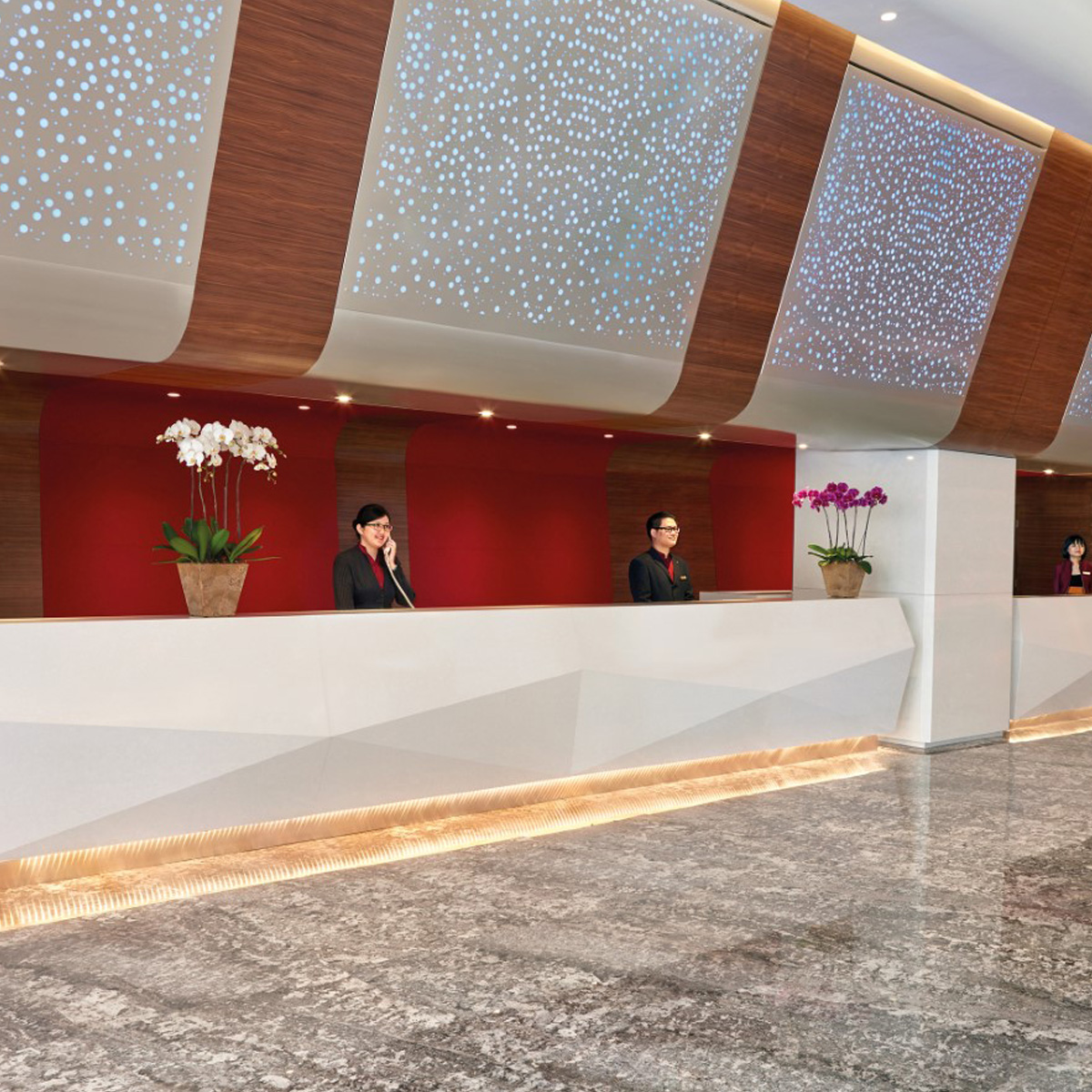 The front office of Sunway Pyramid Hotel where guests may check in, adorned with red walls and lit walls.