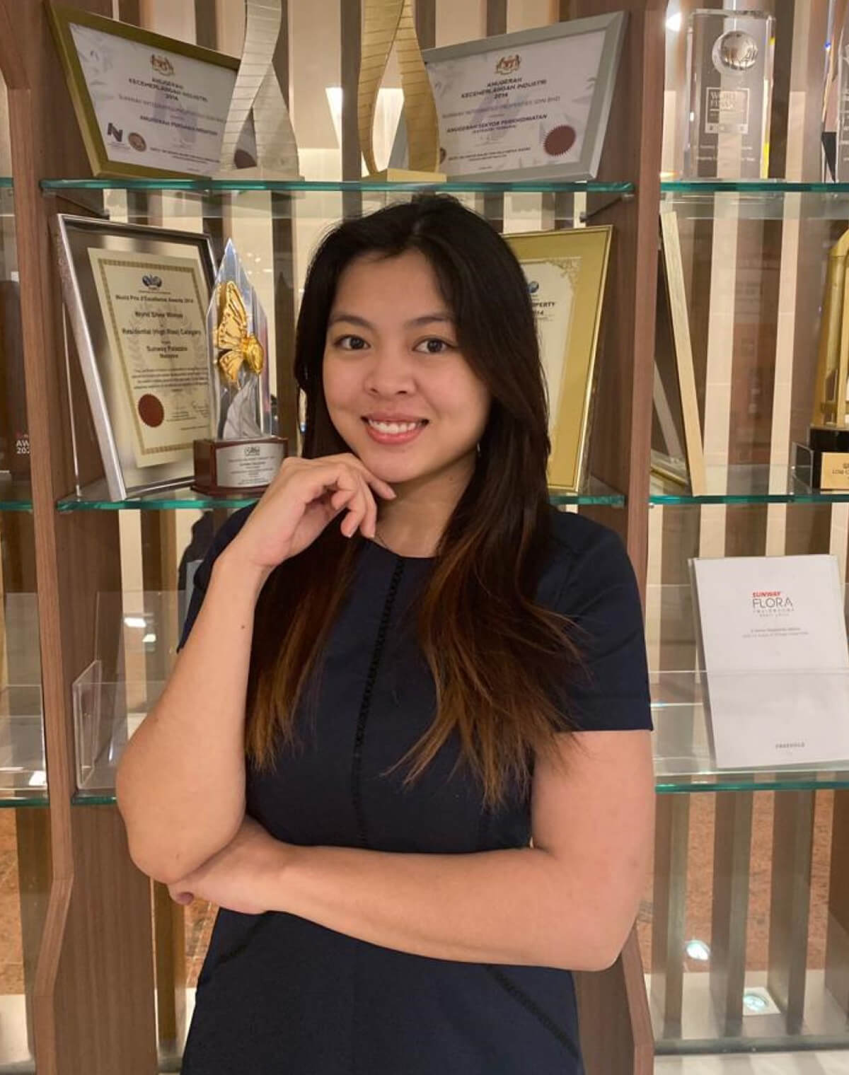 Sunway Property manager of brand strategy and communications Betty Jane Jelia posing in front of the camera, with the awards won in the background