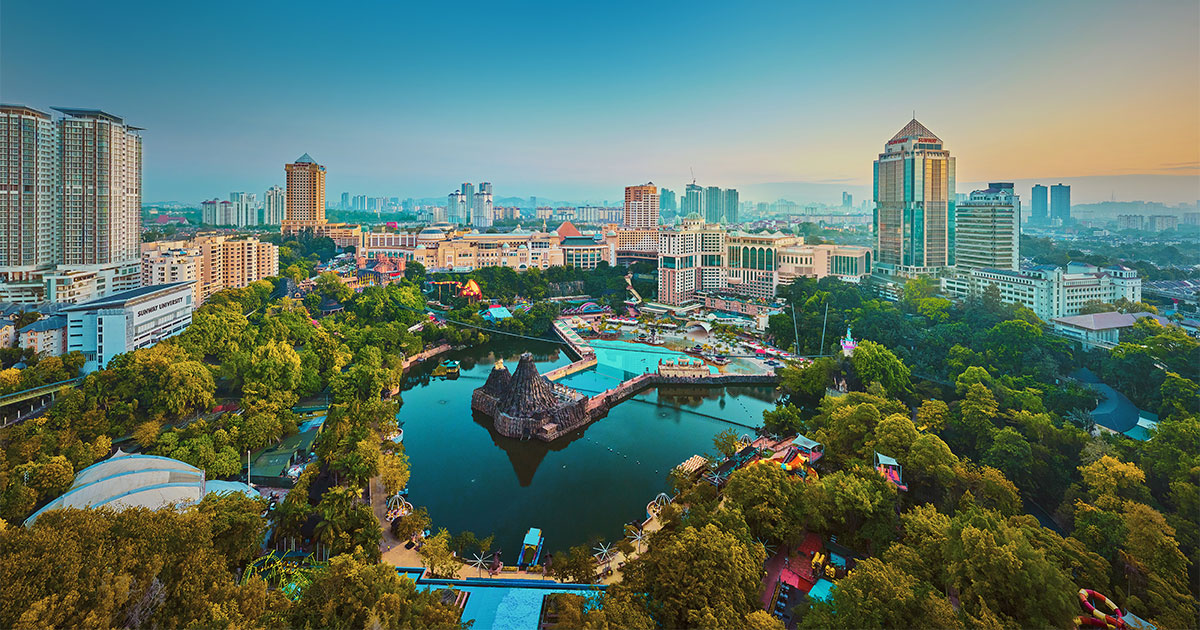 An overview of Sunway Lagoon lake at Sunway City Kuala Lumpur, with other Sunway premises such as Sunway Resort Hotel, Sunway Pinnacle, Sunway University and others beside it, amidst a dawn sky.