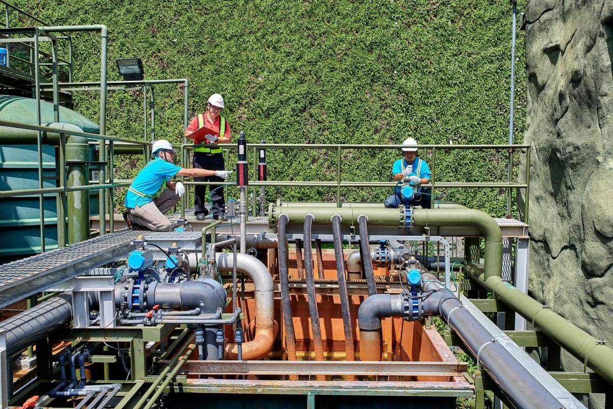Inner workings of Sunway’s water treatment plant, with three men working on the pipes.