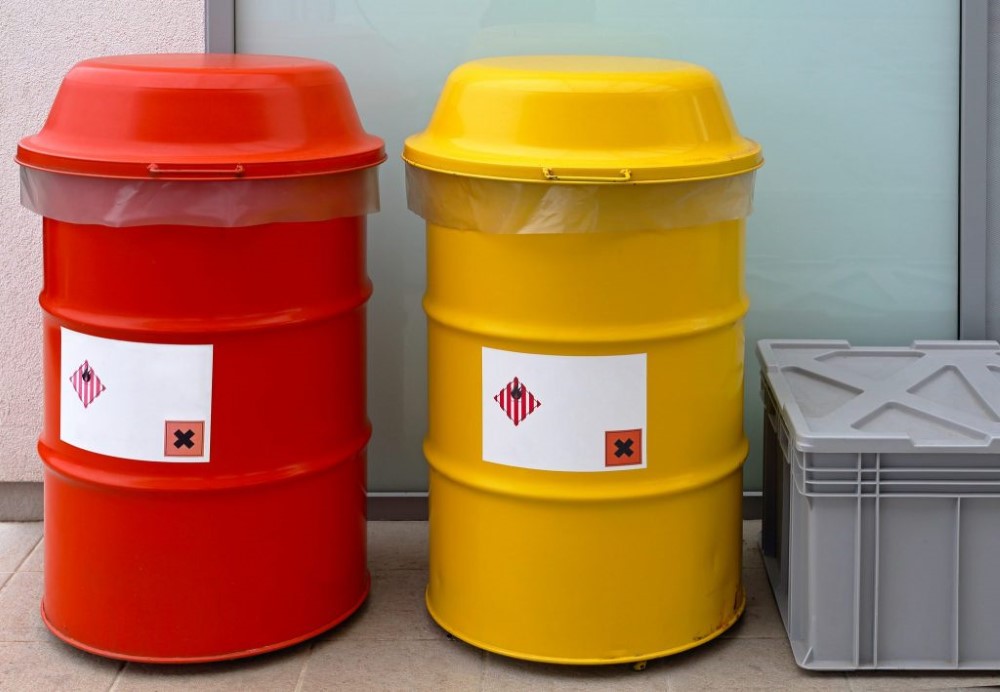 A stock image of two covered biohazard bins used to store potentially hazardous waste materials before proper disposal by licensed contractors