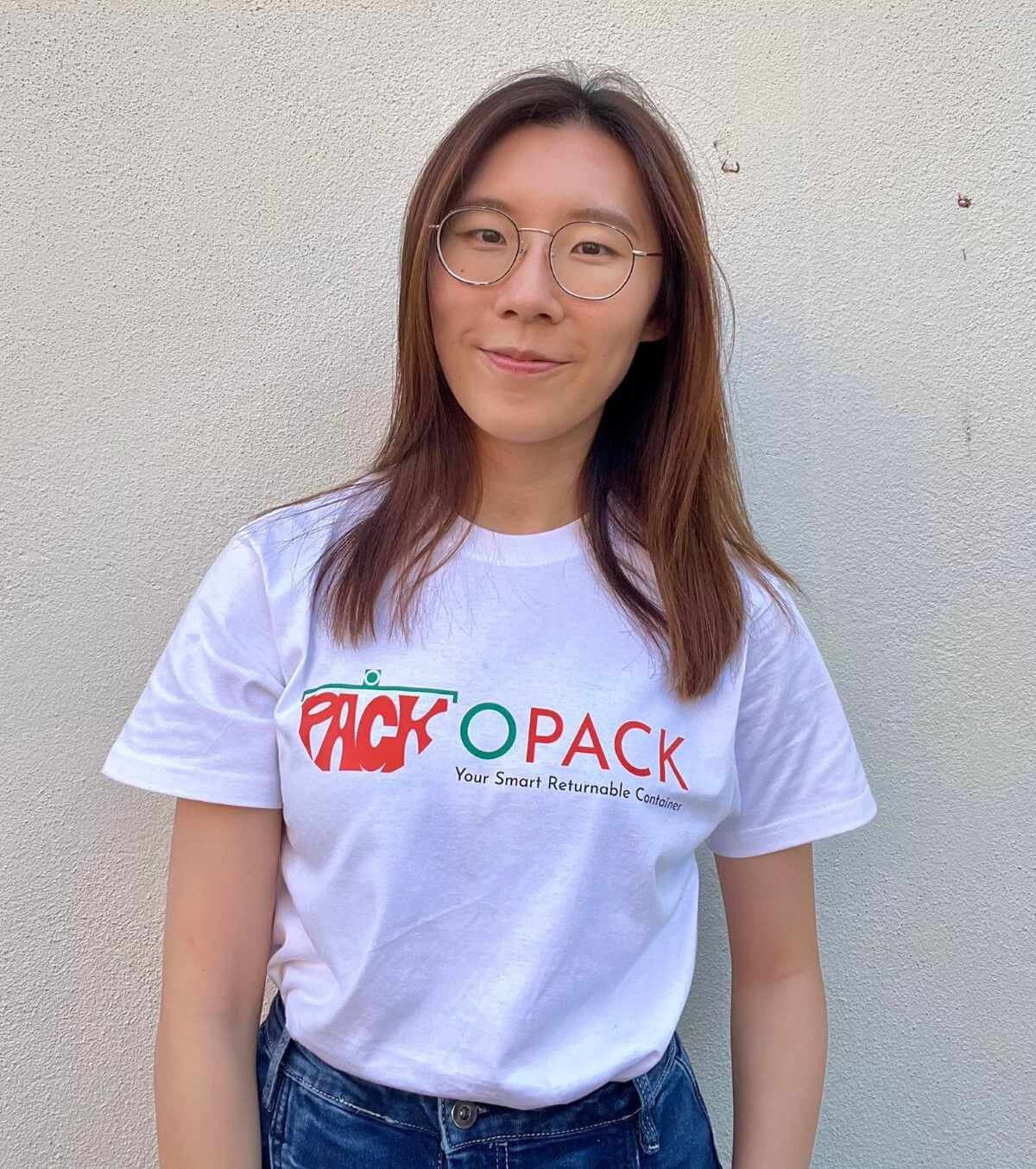 A portrait of OPACK founder Mei Xin standing against a clean, white wall at their local headquarters.