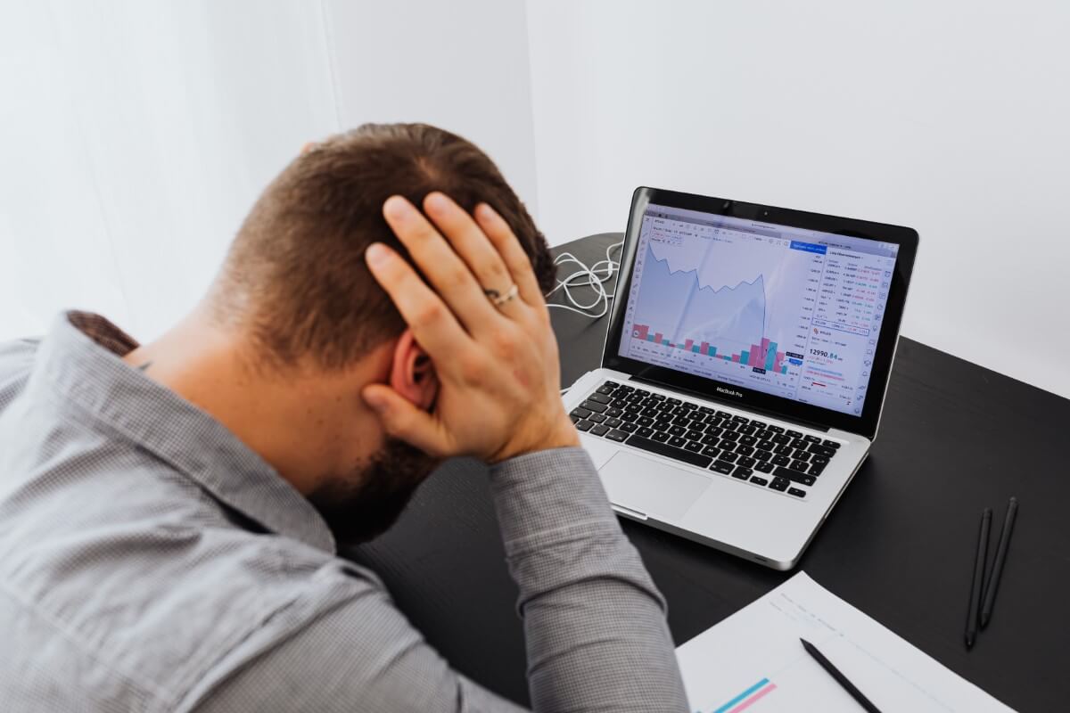 A landscape close-up shot of a man looking visibly daunted by a displayed graph chart on this laptop screen.