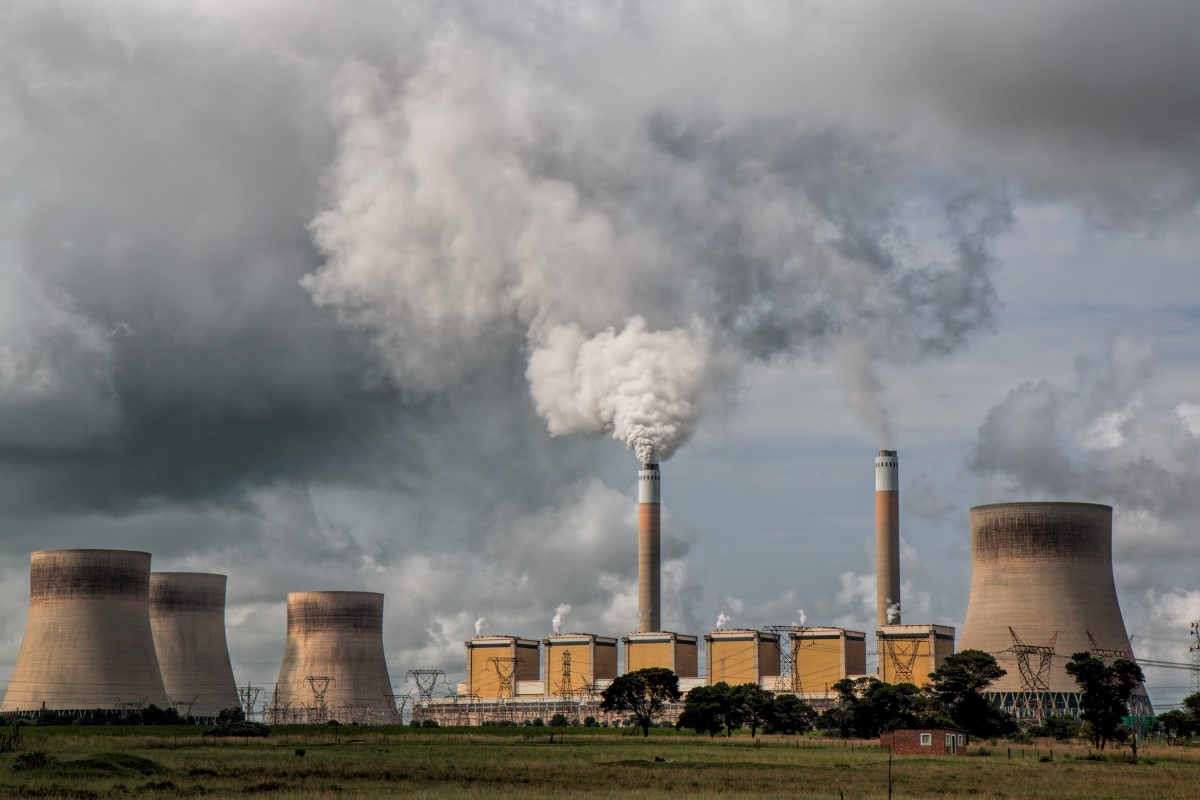 A landscape shot of factory chimneys emitting thick smog to the grey sky above.