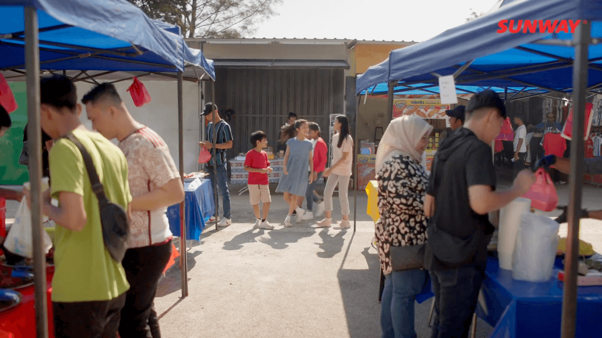 A shot of the five heroes and heroines of Lestari Raya at their local pasar malam, set with blue tenants and pink plastic bags.